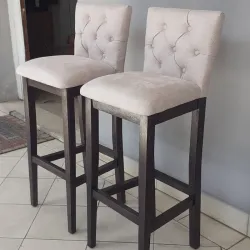 Banqueta de madera con respaldo y asiento tapizados.