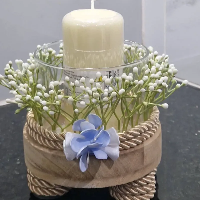 Centro de vela con base artesanal y detalles florales.
