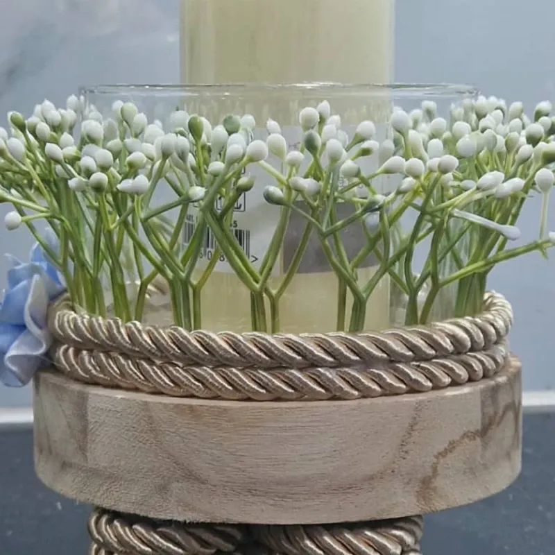 Centro de vela con base artesanal y detalles florales.