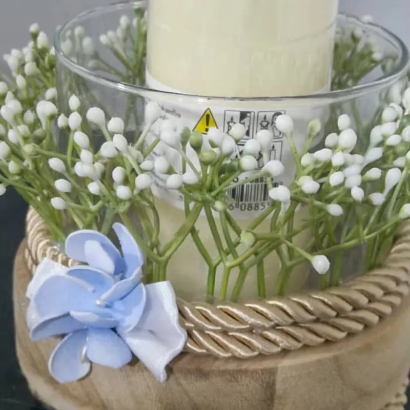 Centro de vela con base artesanal y detalles florales.