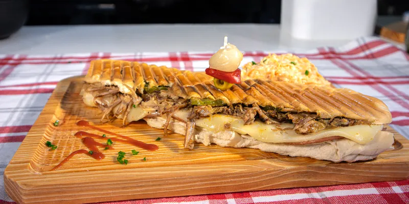Authentica Cubano Sandwich - Roast pork topped with ham, cheese, pickle, mustard, and hot pressed. Served with slaw.