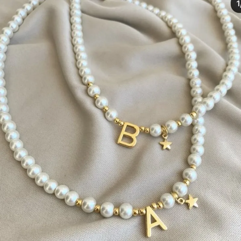 Collares de perlas blancas coco con letra dorada .