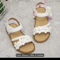 Sandalias blancas de niña contra florecita