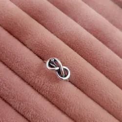 Anillo de infinito con pequeña piedra oscura incrustada.